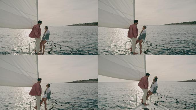 落日时分，一对富有的年轻夫妇在帆船的船头上放松