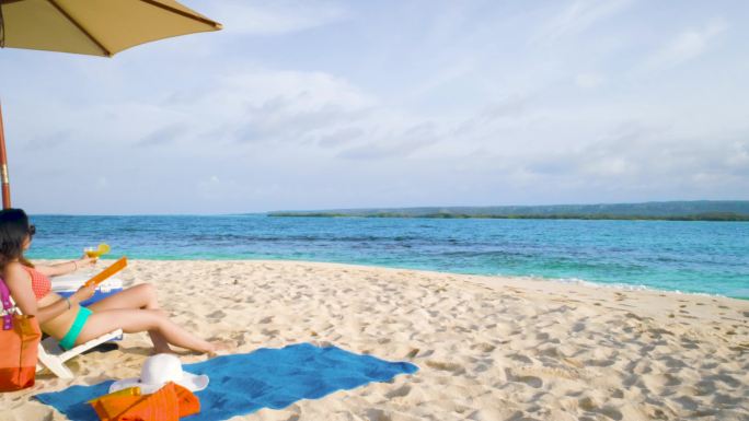 放松的西班牙裔年轻女子坐在热带绿松石加勒比海礁上晒日光浴