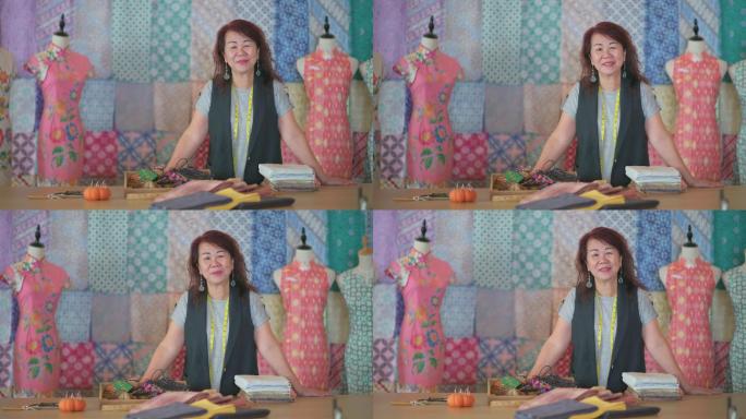 马来西亚华裔成熟女性精品店小企业主画像在她的蜡染旗袍面料纺织品零售店前微笑着看着相机