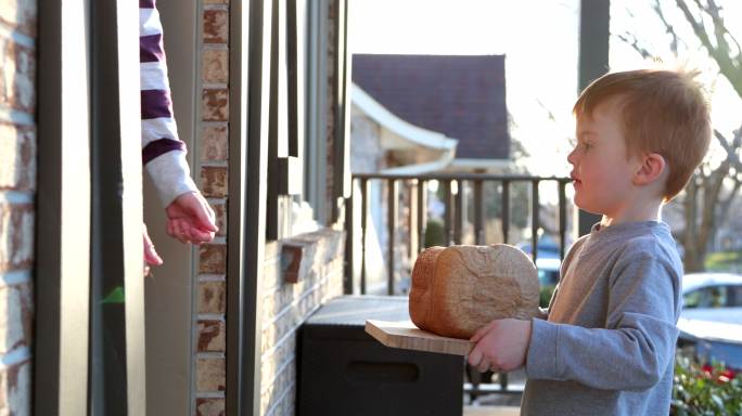 年轻可爱的红头发孩子把自制面包带到邻居家门口