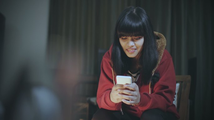 单身年轻女子晚上使用智能手机。