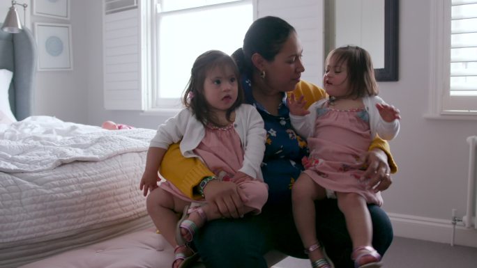 一位母亲和她的两个年幼的女儿坐在卧室的家里