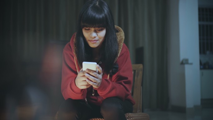单身年轻女子晚上使用智能手机。