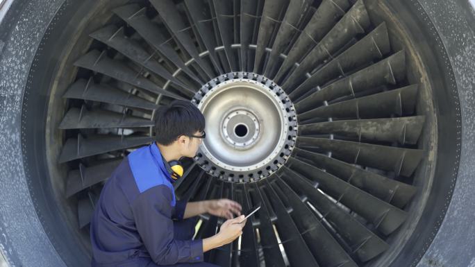 男性飞机工程师使用数字平板电脑检查喷气发动机