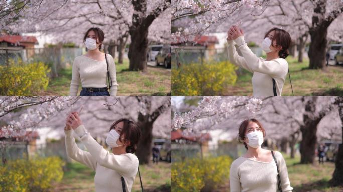 戴防护面罩的年轻女子拍摄日本樱花