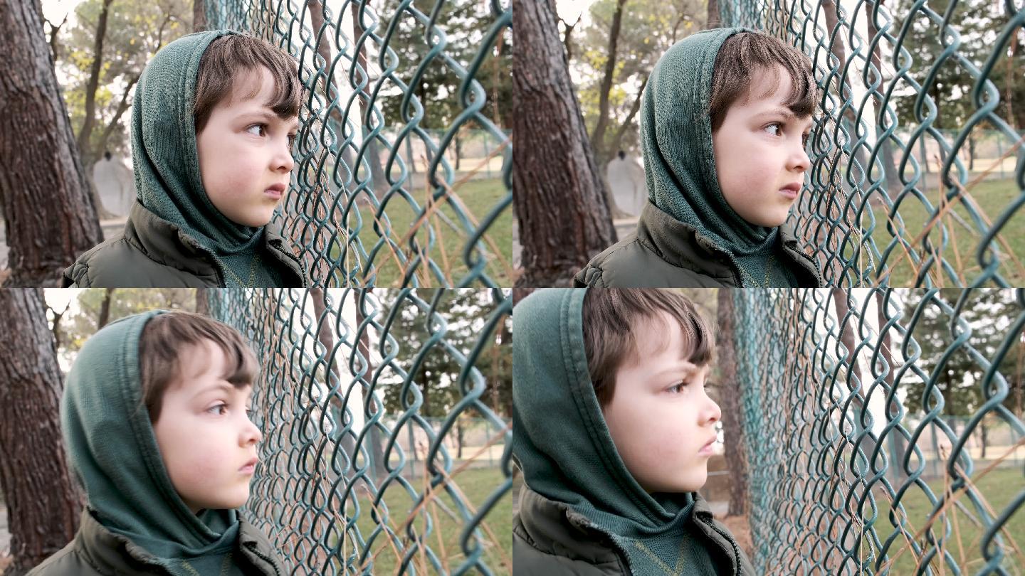 严肃沉思的孩子透过栅栏看