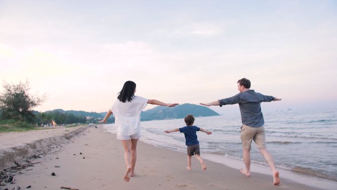 周末，幸福的一家人在海滩散步和跑步。