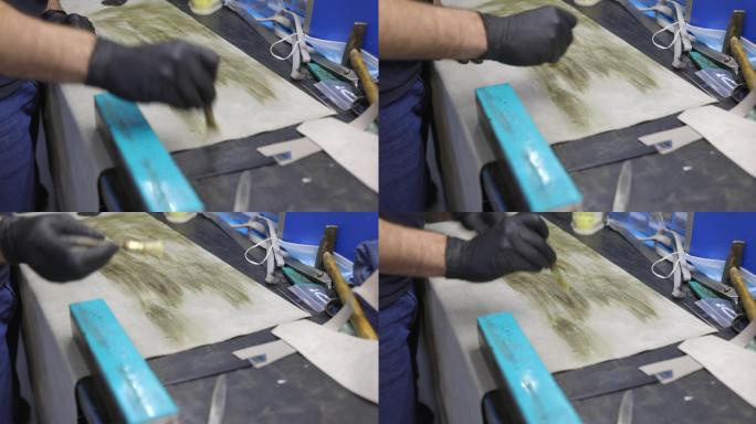 工艺维修车间工作台上用刷子在皮片上涂胶