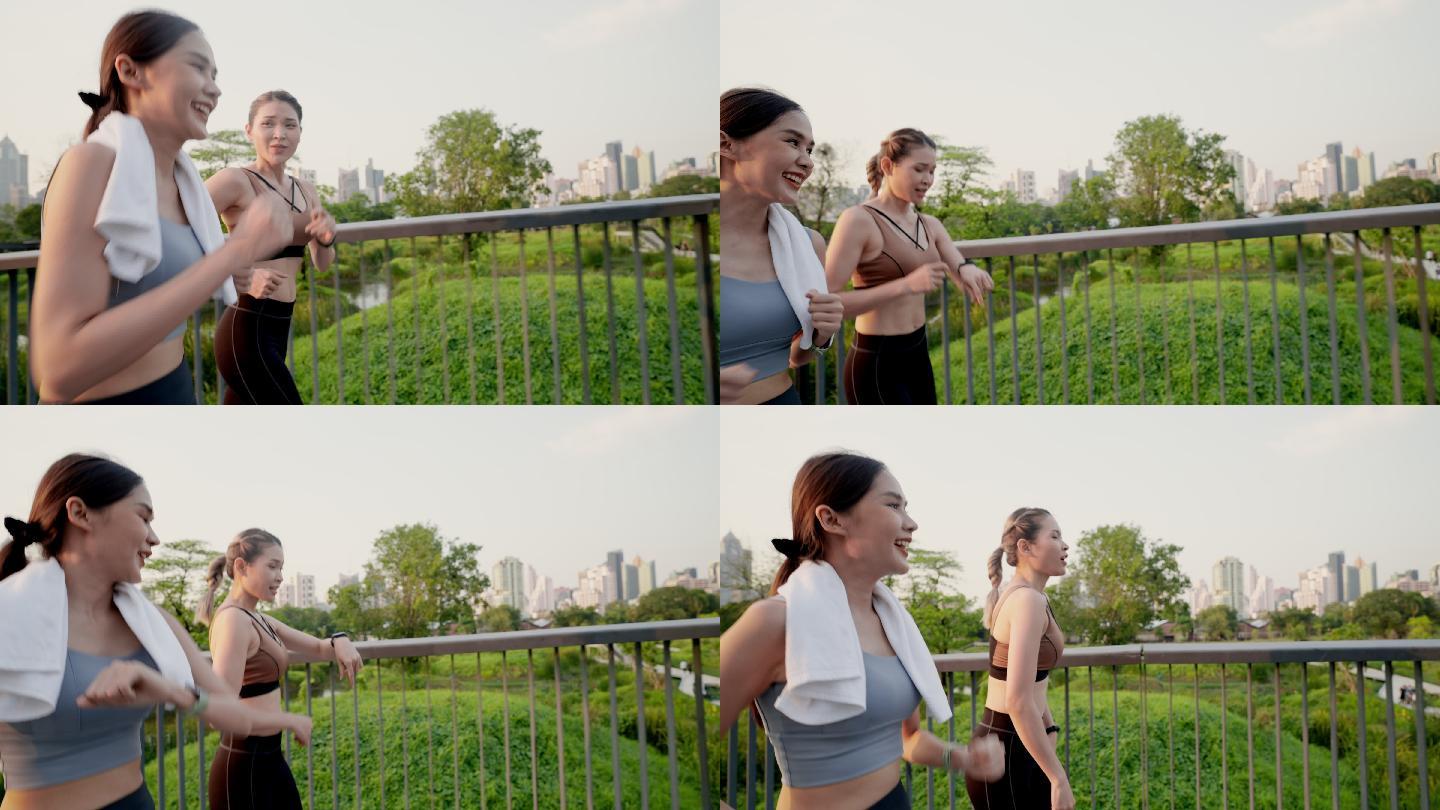 侧视图：两位亚洲美丽的中年女性朋友穿着运动装，拥有完美的肌肉，早上在市中心附近的公园花园的人行天桥上