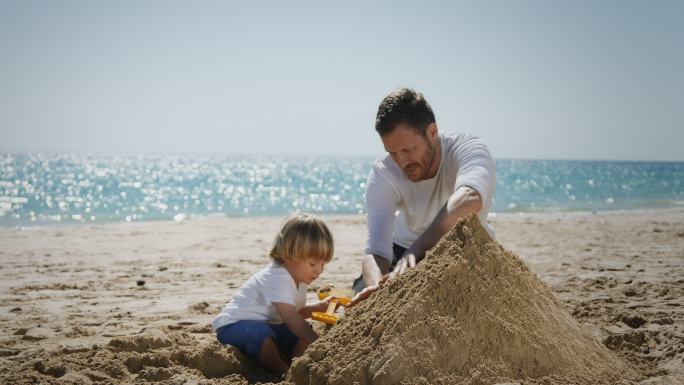 海滩上的父子父子堆城堡沙滩城堡父子海边做