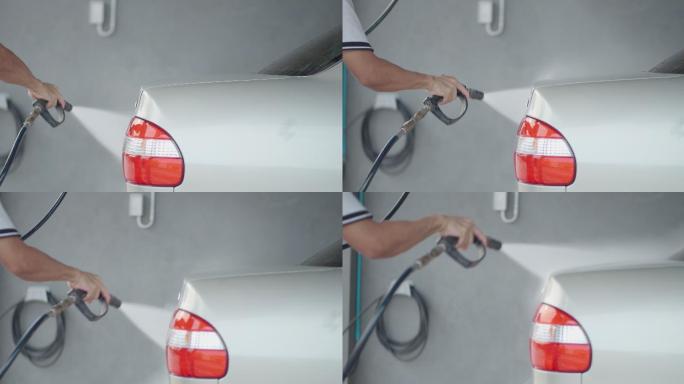 一名亚洲人在家用水泵的压力喷雾器洗车