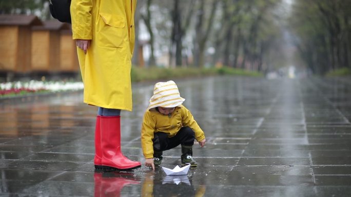 孩子和妈妈在水坑里玩纸船