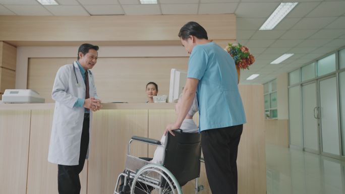 男护理助理轮椅与患者关切地交谈。在医院或诊所