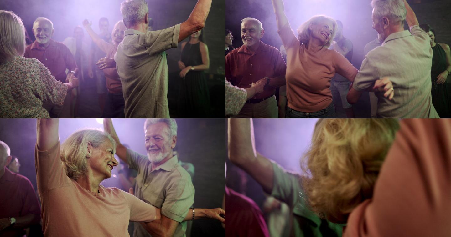 快乐的成年情侣在迪斯科舞厅跳舞。
