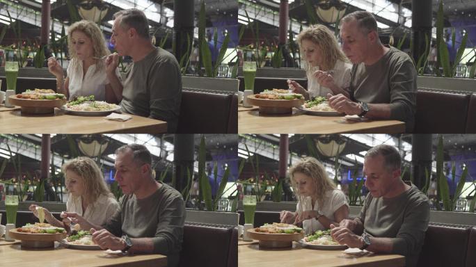 一对年纪较大的拉丁夫妇在一家餐厅里享受着他们的情侣时光，看着手机上拍摄的照片
