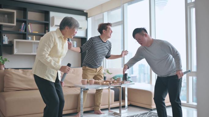 周末，多代亚裔中国男子在客厅与唐氏综合症儿子跳舞，与祖母唱歌跳舞，玩得很开心