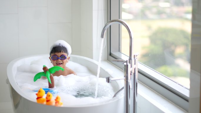 亚洲孩子在酒店的浴缸里玩着通气面罩和黄鸭子。健康与幸福的概念