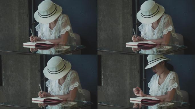 戴着白帽子的美丽艺术家在笔记本上画素描，她的作品在家里反射着玻璃桌