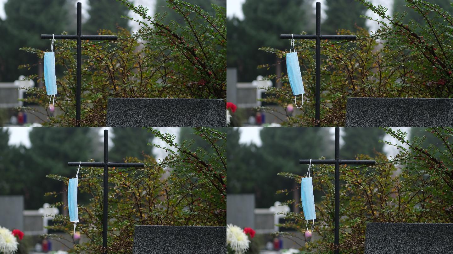 墓地上黑色铁十字架上的蓝色一次性面罩。冠状病毒死亡。