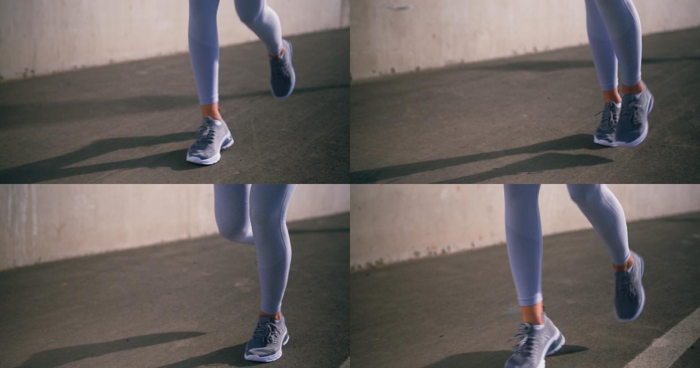 一只穿着白色紧身裤的女性双腿在柏油路上奔跑的特写镜头
