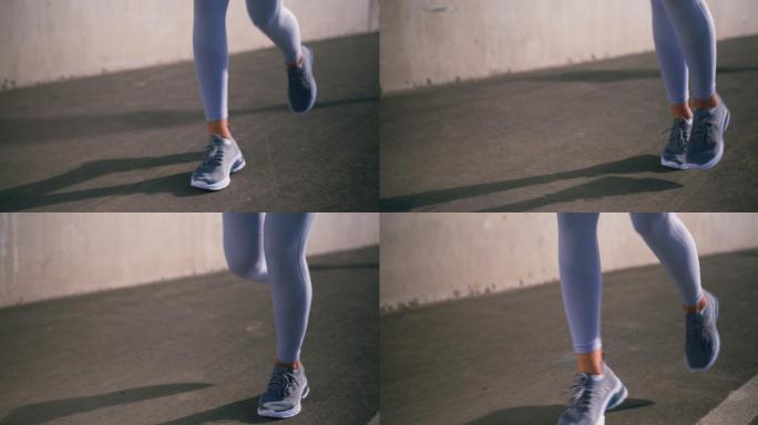 一只穿着白色紧身裤的女性双腿在柏油路上奔跑的特写镜头