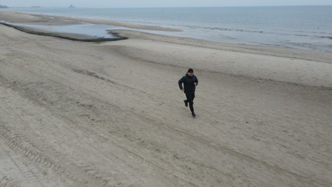 冬季在德国北海海滩上奔跑的男子