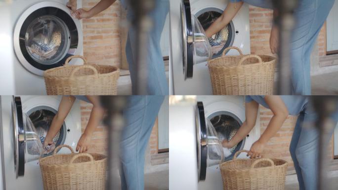 做家务的亚洲女人。洗完衣服后，妇女从洗衣机滚筒中取出衣服在家晾干。