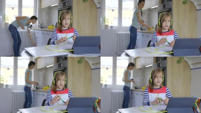 小学女孩在家里用数字平板电脑在线上课时戴着耳机接听电话