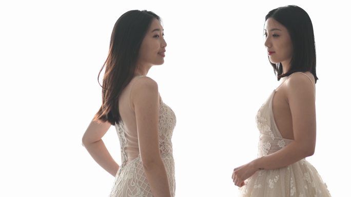慢镜头2：穿着婚纱的美女在婚纱店摆姿势，在白色背景下微笑