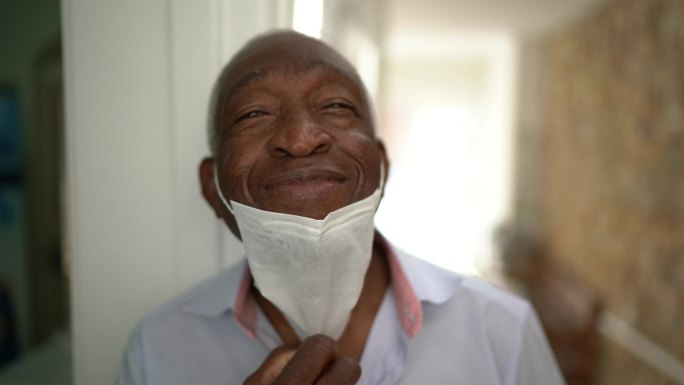 一位老人摘下面罩微笑的肖像