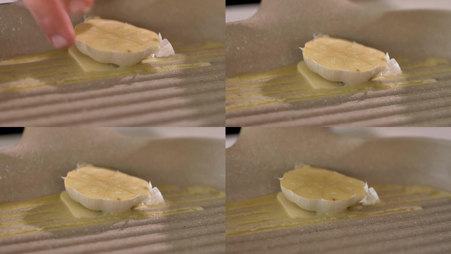 厨师在烤盘中融化的黄油中加入半个蒜头