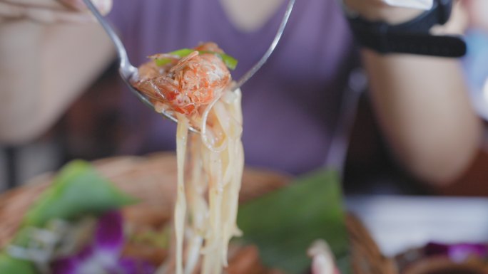 特写镜头：在盘子上用叉子和勺子吃虾垫泰式面条，在旧的绿松石木板桌上吃香蕉叶，面条是用新鲜的水和蒸汽制
