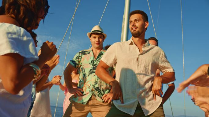 日落时分，两个男人在游艇上和朋友们一起跳舞，玩得很开心