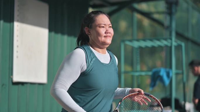 周末早上，亚裔中国中年女子步行回网球场参加另一场比赛