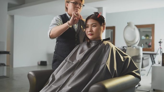 慢动作美发沙龙亚洲华人女发型师在美发沙龙为顾客剪头发梳理湿长发