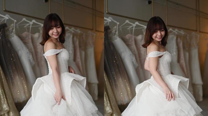 快乐自豪满意的亚洲华人新娘肖像摆姿势看着相机在婚纱店微笑着试穿婚纱