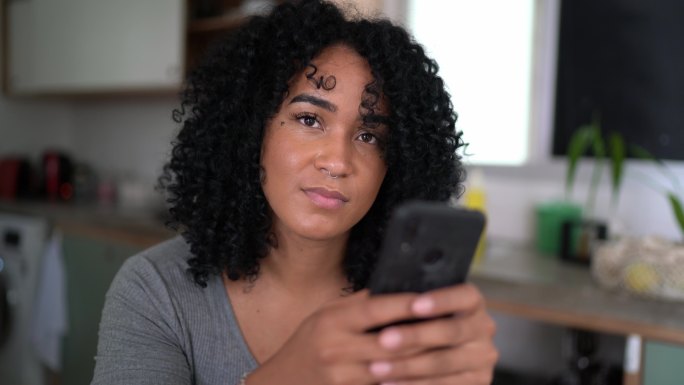 一位年轻女子在家里用智能手机发短信的照片