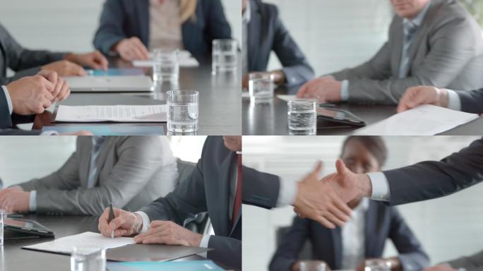 坐在对面的两位商人的手，在同事面前签署合同并握手