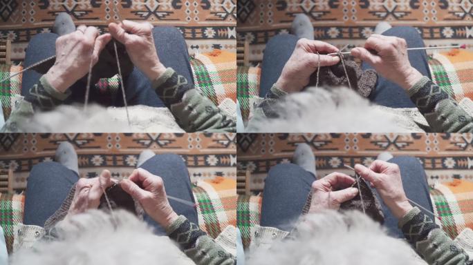 POV。一位老年人编织精细美观，一位奶奶双手布满皱纹的特写镜头，正在制作一件新的冬季毛衣，积极的退休