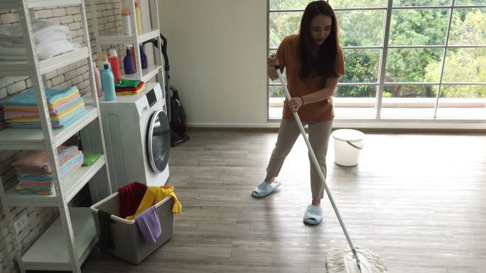 女清洁工用拖把打扫家里的房间
