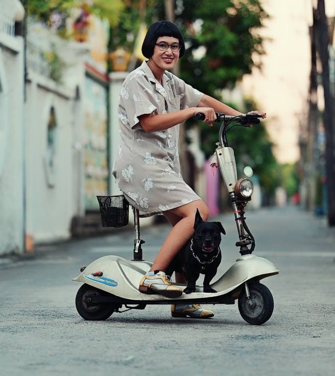 带着她的狗在城里骑电动滑板车的女人