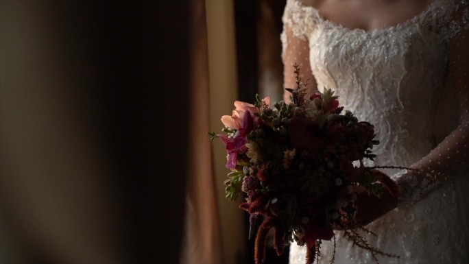 婚礼前，新娘手持花束，透过窗户观看