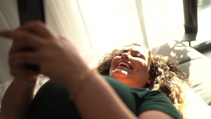 幸福女人在家里用智能手机躺在床上