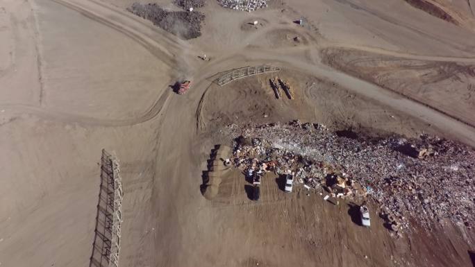 从空中拍摄到一辆自卸车在卸下一车垃圾后驶出垃圾填埋场