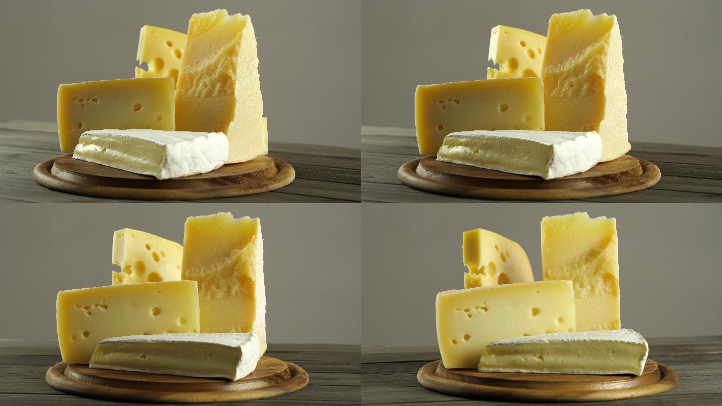 不同类型的奶酪，法国布里干酪，瑞士奶酪，意大利帕尔马干酪，圆形木制砧板上的一组奶酪片