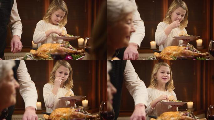 孩子在享受她的感恩节火鸡片，她的爷爷为她服务