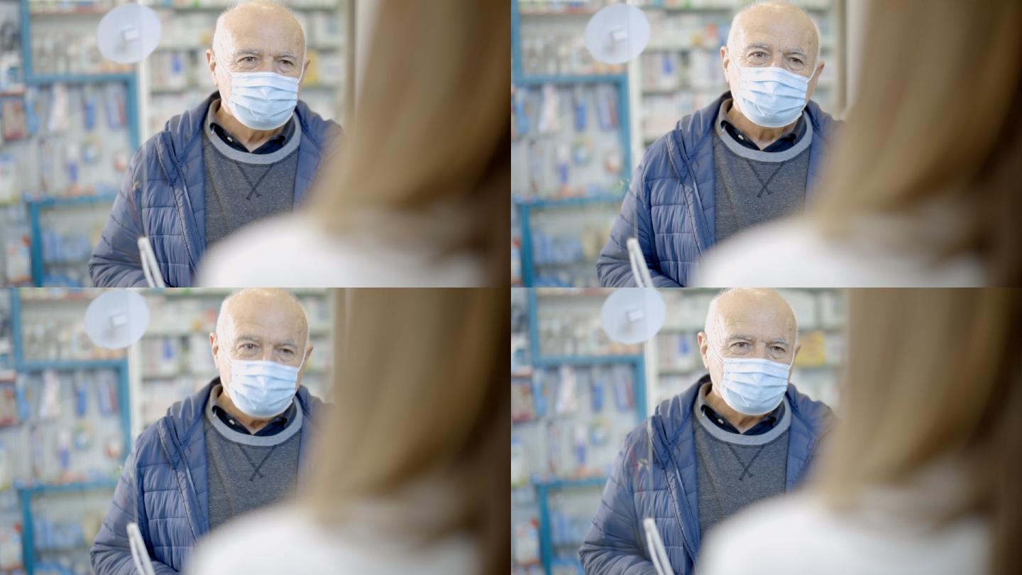 戴口罩的老人站在药房里，一边说话一边接受女药剂师的建议