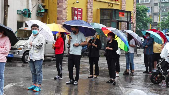 城市大雨中打伞排队的市民人群