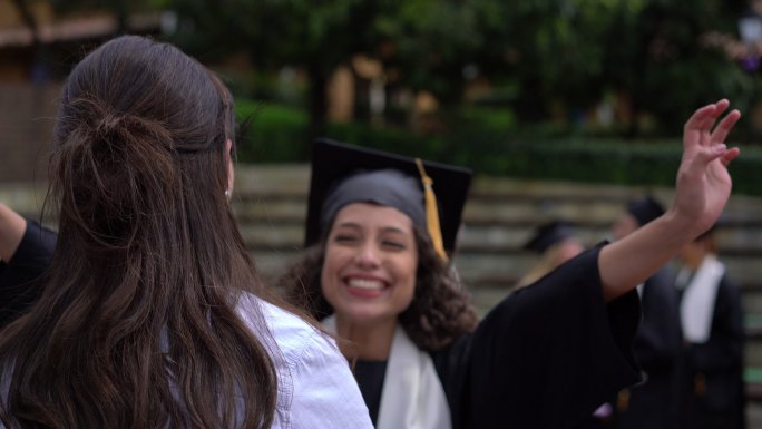 获得大学学位后，一个快乐自豪的学生跑去拥抱她的妈妈