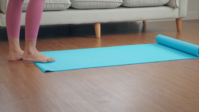 特写镜头：一位女士在蓝色瑜伽垫上伸展双脚